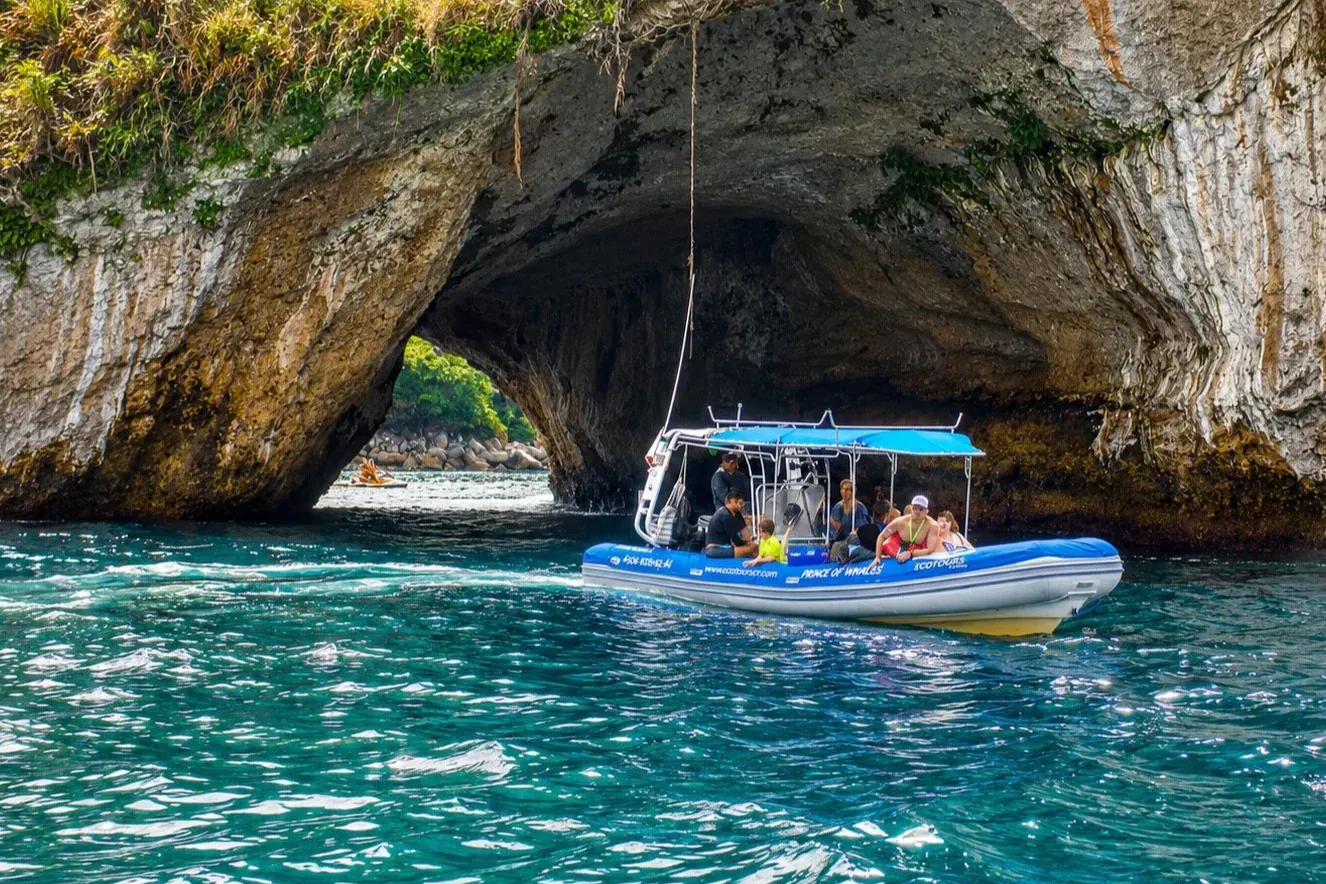 Small Ecotours group boat passing through a rock arch in Banderas Bay