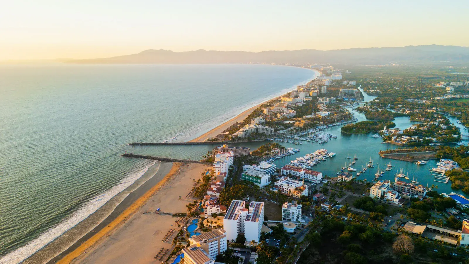 Aerial view of Banderas Bay at sunset, showing the beach, marina and mountains in the background