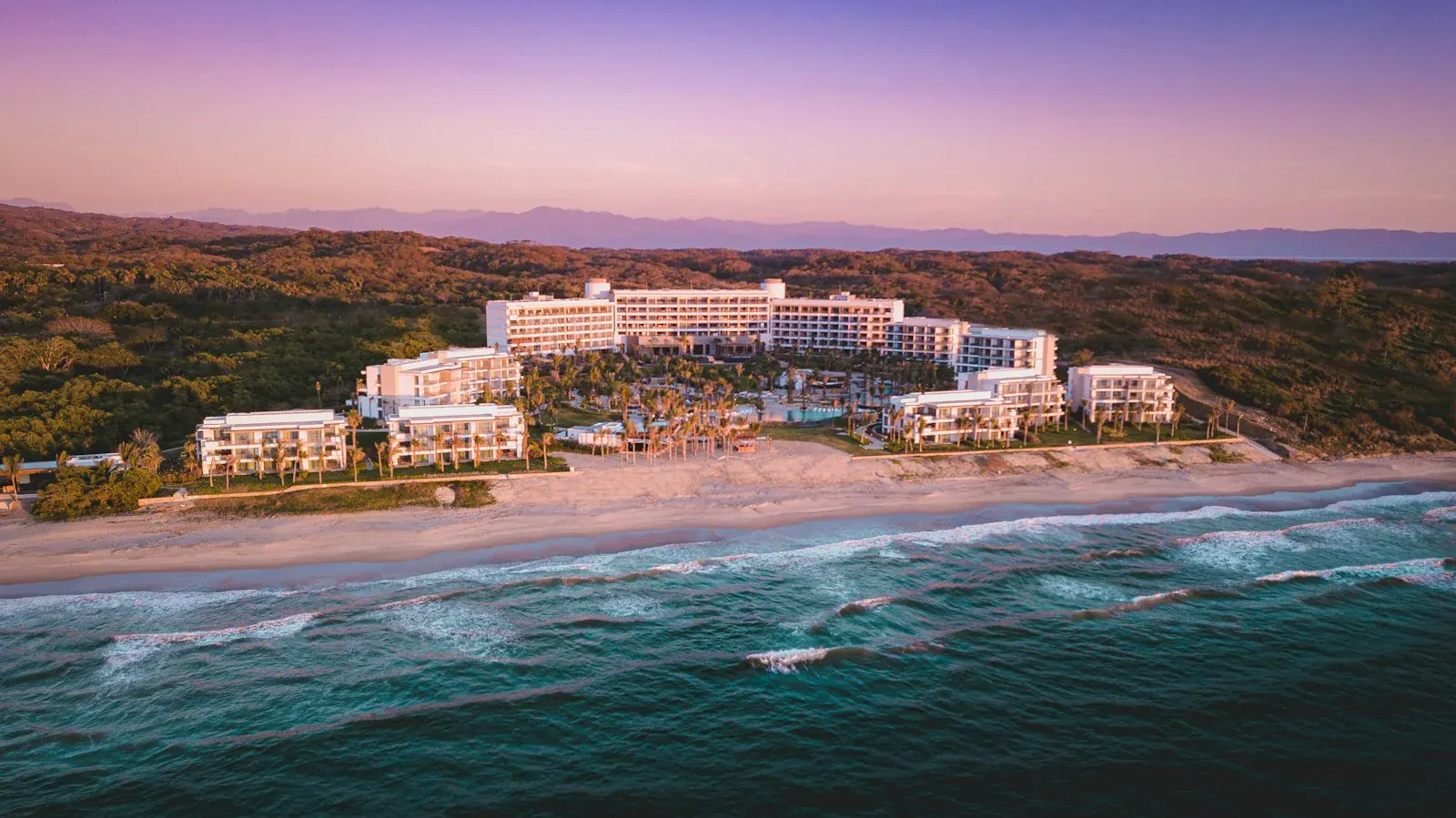 Beachfront resort in Riviera Nayarit at sunset, with hills and mountains in the background