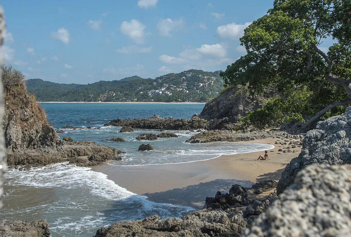 Rocky cove along the Banderas Bay coastline, with a coastal community visible on the hillside in the background