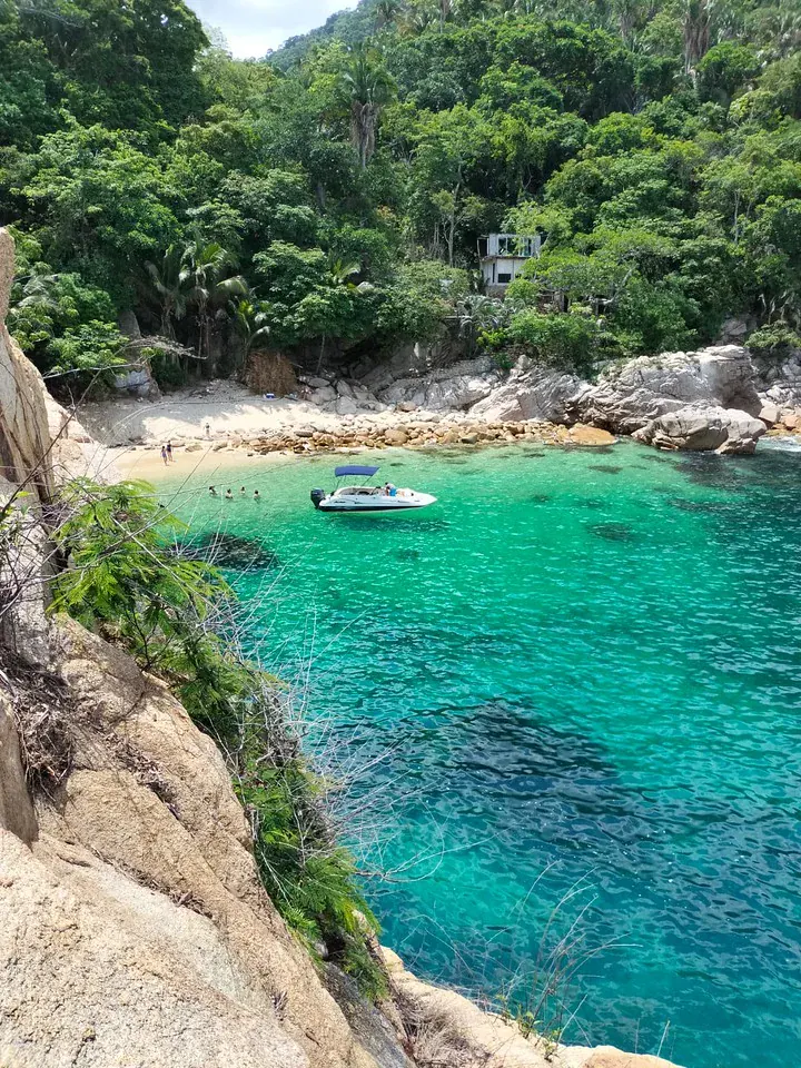 Ecotours boat anchored in a hidden cove on the south coast, with swimmers in the water