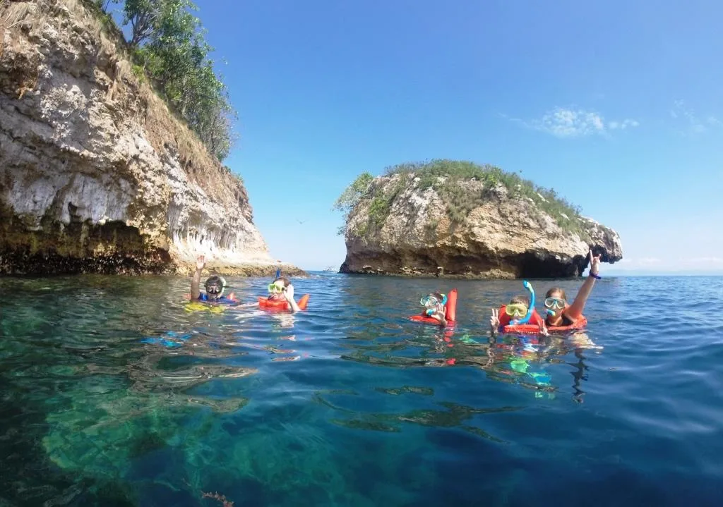People snorkeling in clear water with tropical fish