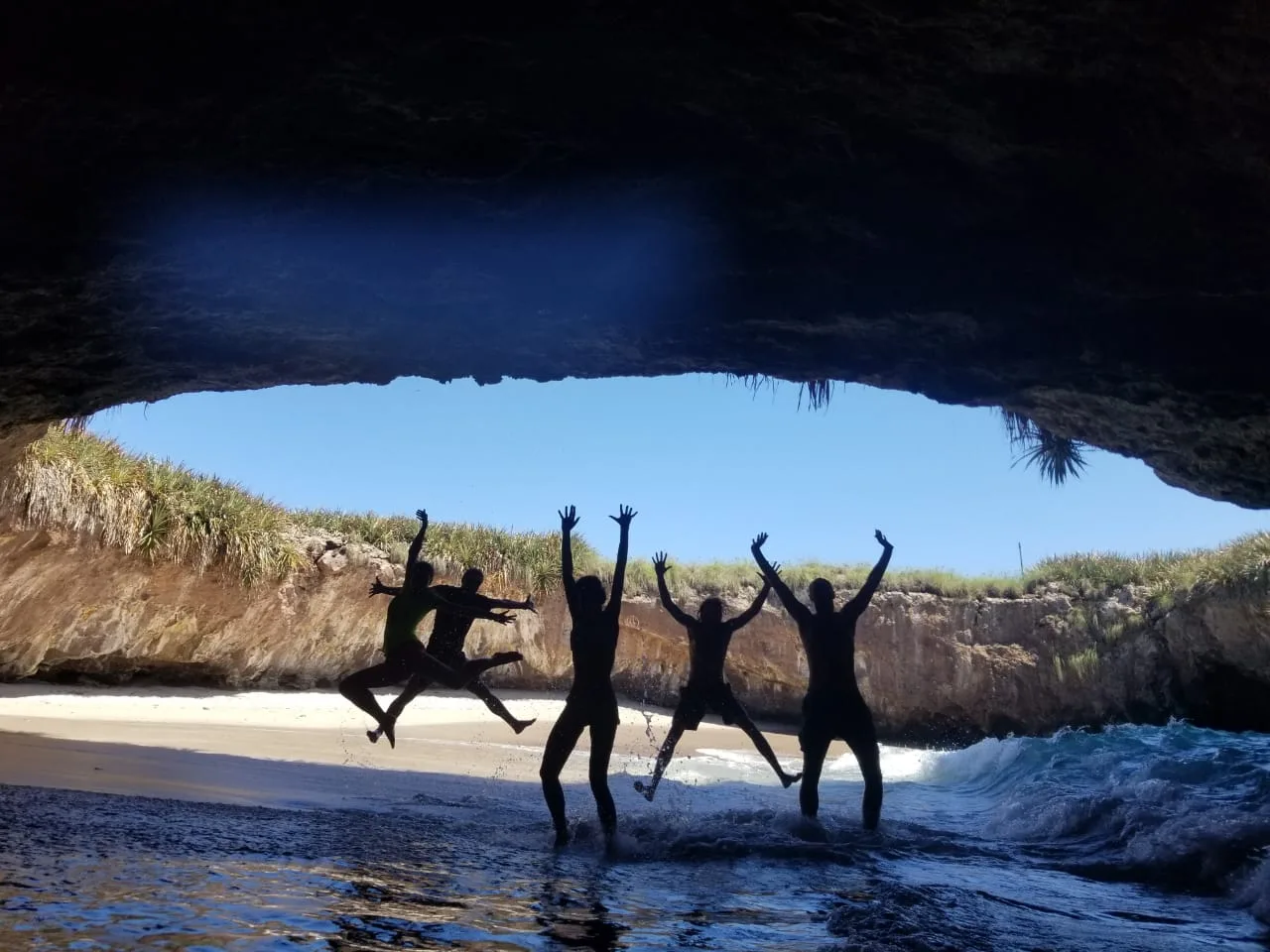 Friends jumping into the water inside a sea cave in Puerto Vallarta