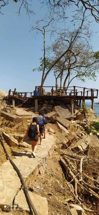 Hikers with backpacks walking the rocky trail above the coastline