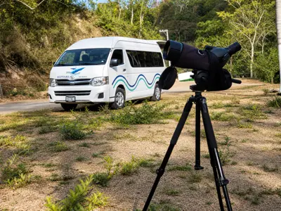 Ecotours van parked on a dirt road with a spotting scope set up in the foreground