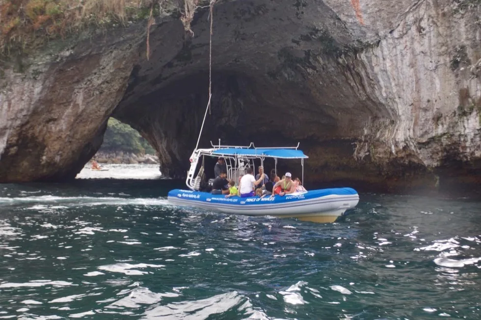 Tour boat entering a rock cave at Los Arcos