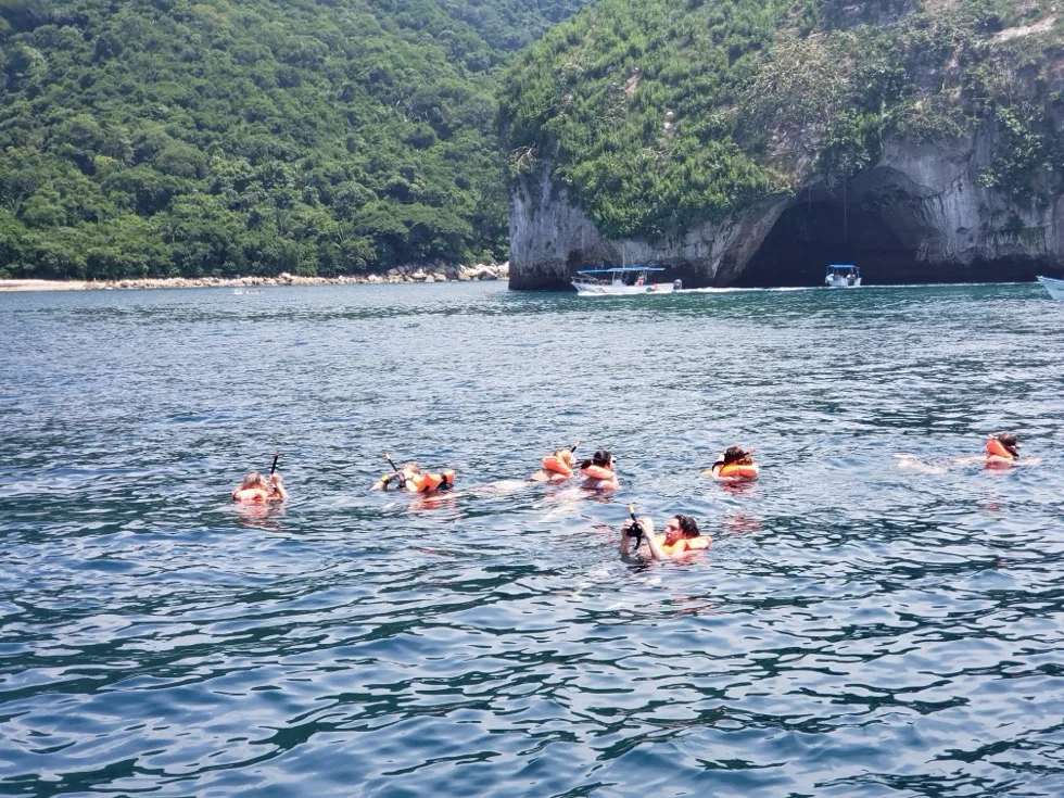 Guide helping guests put on snorkeling fins aboard the boat