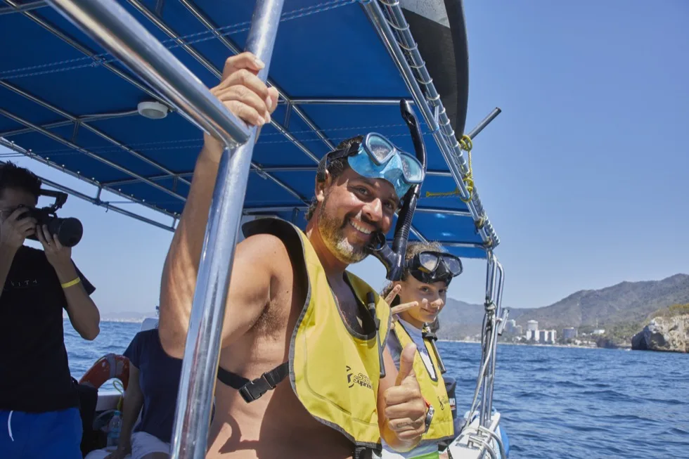 Guests paddleboarding and snorkeling near a rock arch