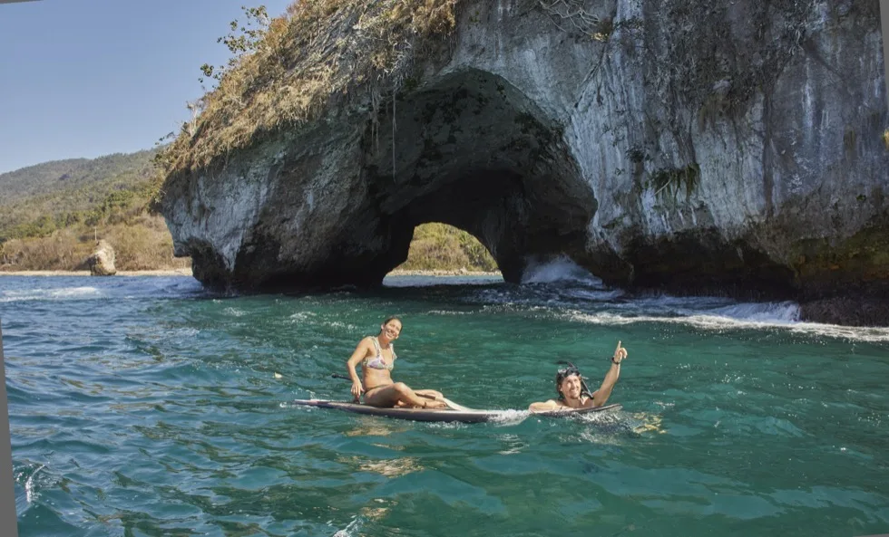 Guests paddleboarding beside the Los Arcos rock formations