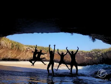 Friends jumping for joy on the hidden beach at Islas Marietas