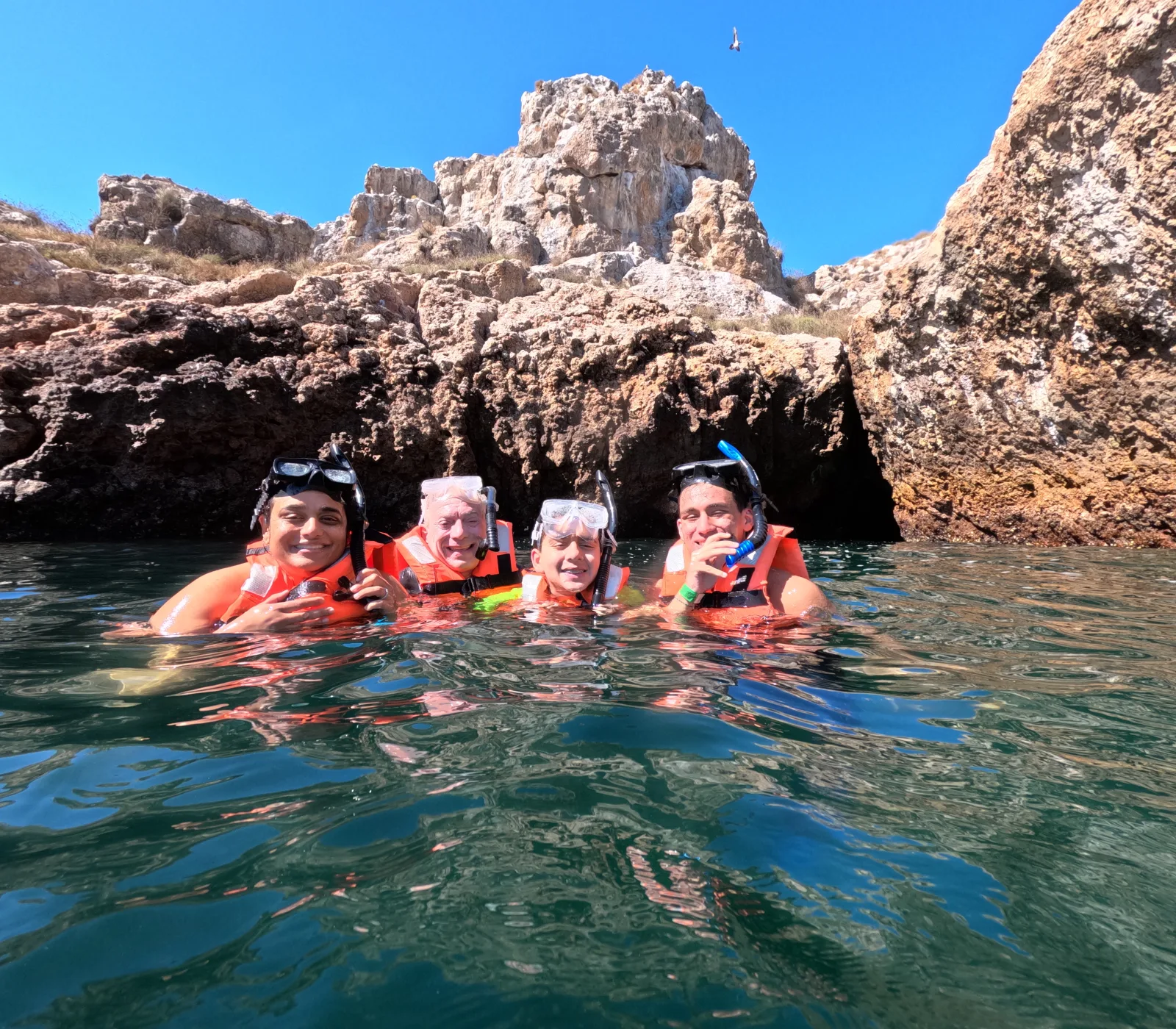 People snorkeling beside rock formations