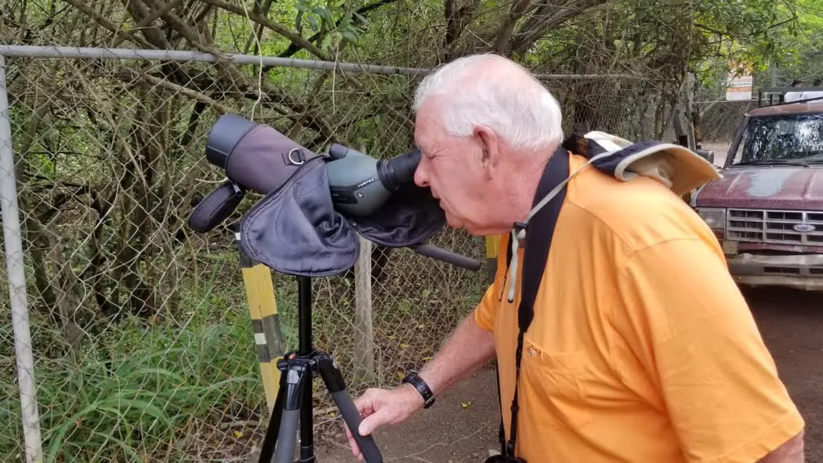 Birdwatcher observing through a spotting scope at the Military Macaw Sanctuary