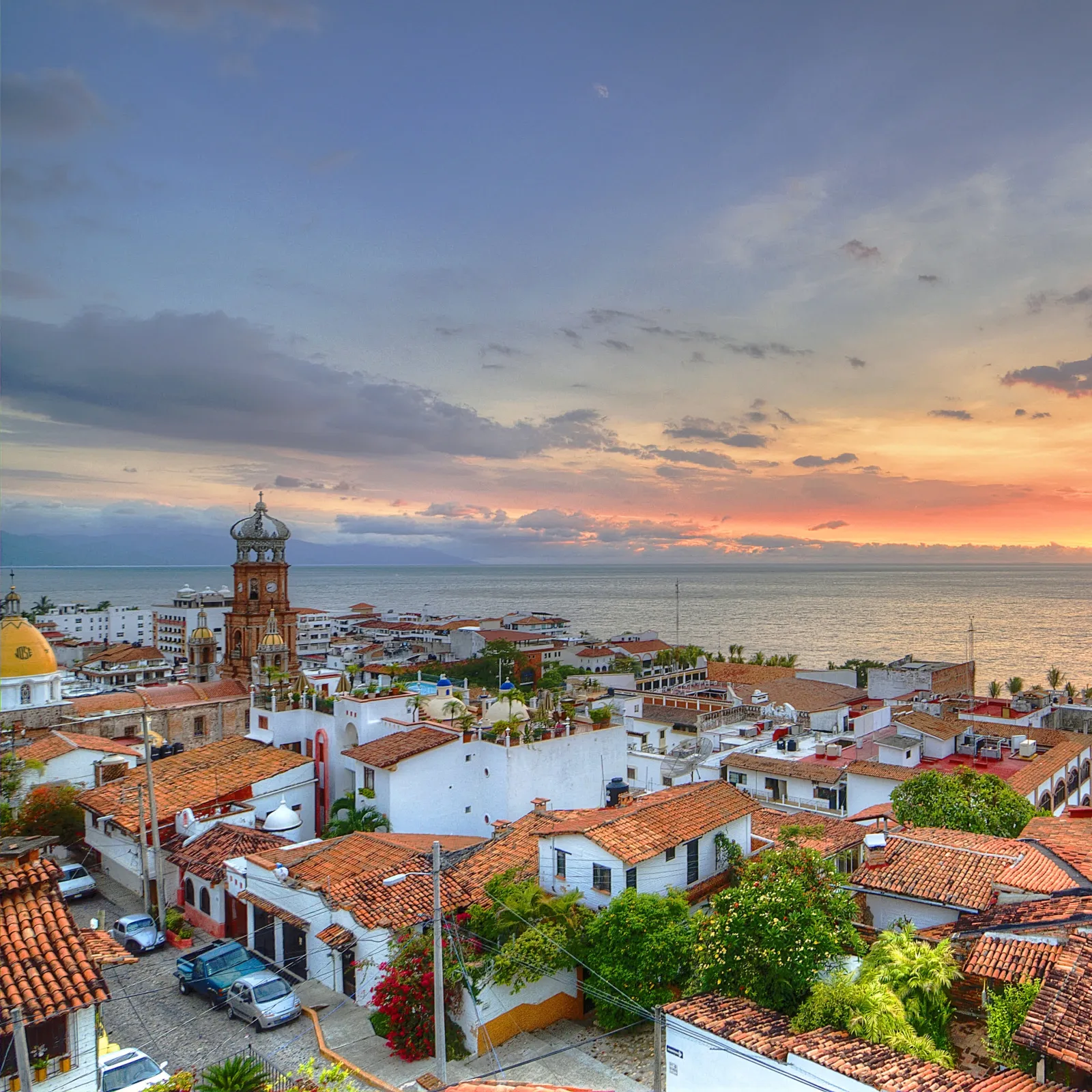Sunset over Puerto Vallarta showing the ocean, the Historic Center and tile roofs