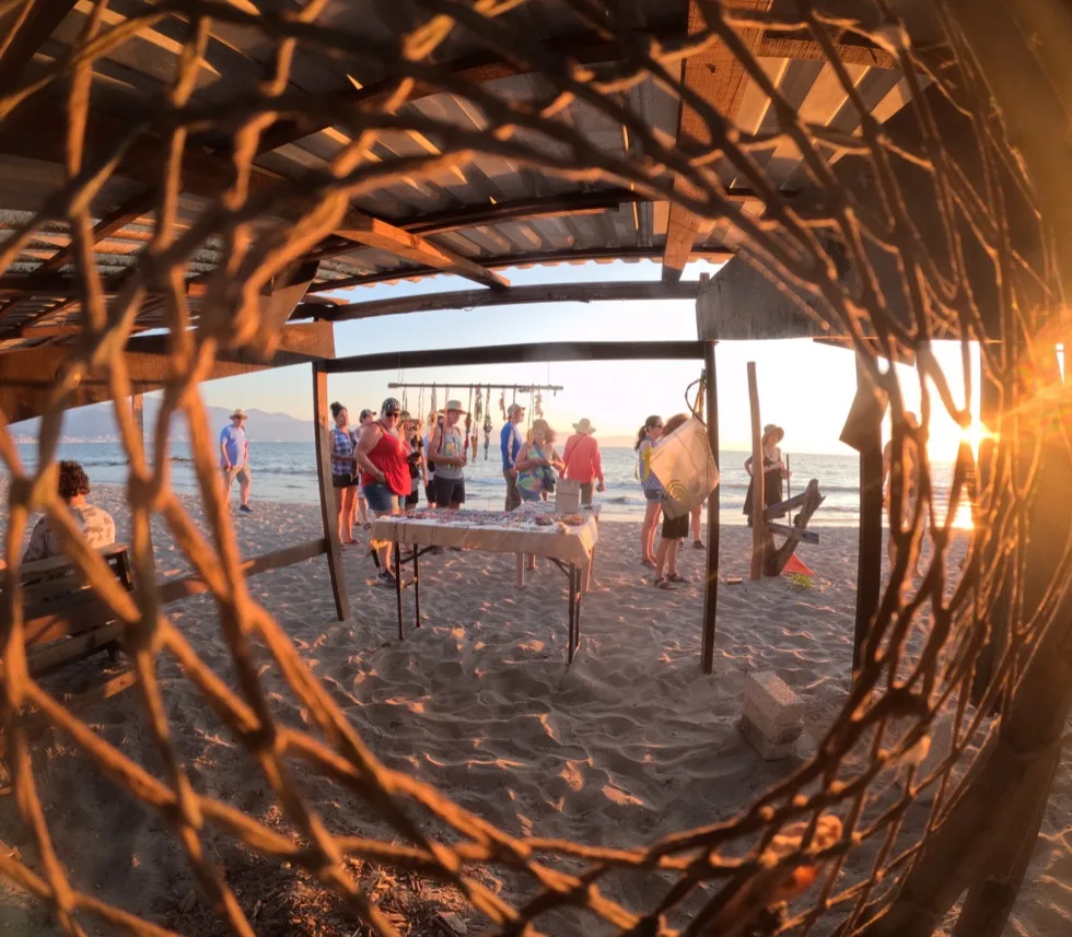 Guests browsing a beachside stand at sunset near the turtle camp
