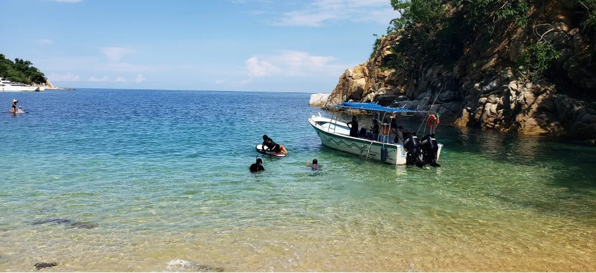 Snorkelers and a paddleboarder next to the private boat off the Yelapa coast